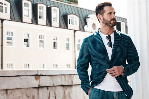 a stylish man wearing a striped blazer, white tee and denim jeans