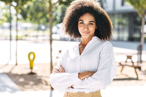 a woman standing outside wearing a white shirt and sand coloured pants