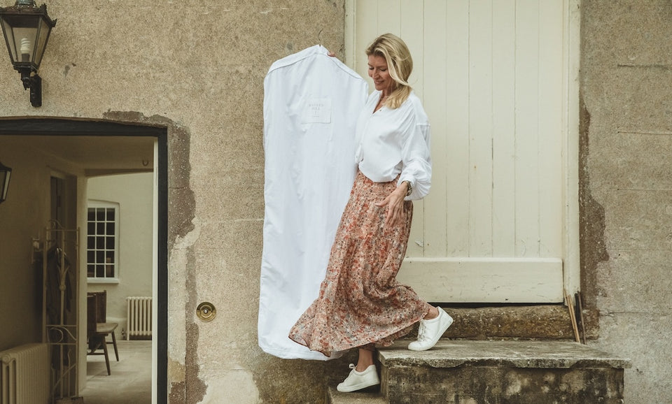 a woman walking down steps carrying a Hayden Hill long hanging garment bag