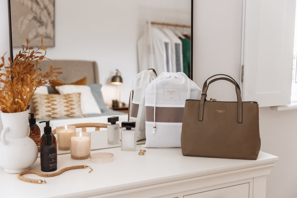 a brown handbag sitting with a Hayden Hill dust bag on a dressing table