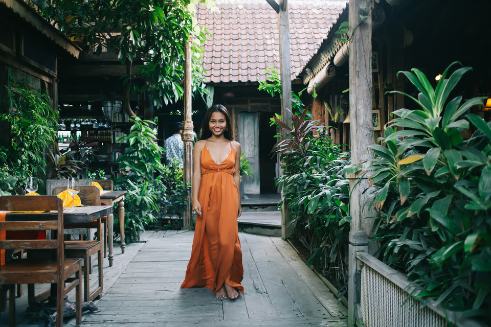 a beautiful woman wearing a stunning silk rust coloured strappy maxi dress