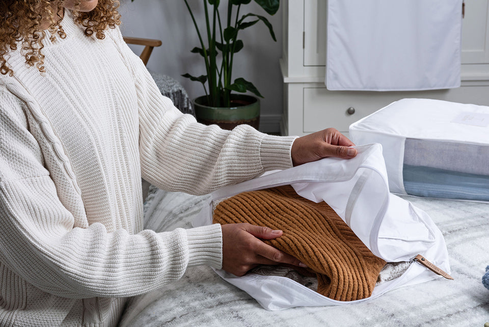 a close up of a woman putting her woolens into a Hayden Hill Cotton Storage Bag