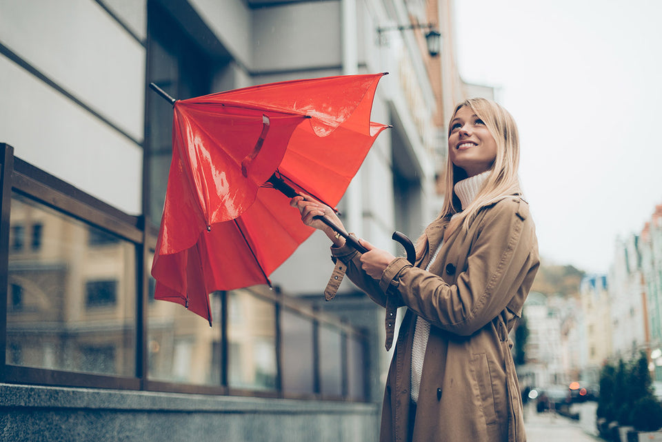 a woman in a raincoat closing her umbrella after the rain