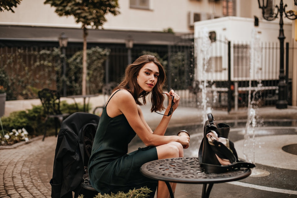 a stylish woman sitting at an outdoor table wearing a silk slip dress