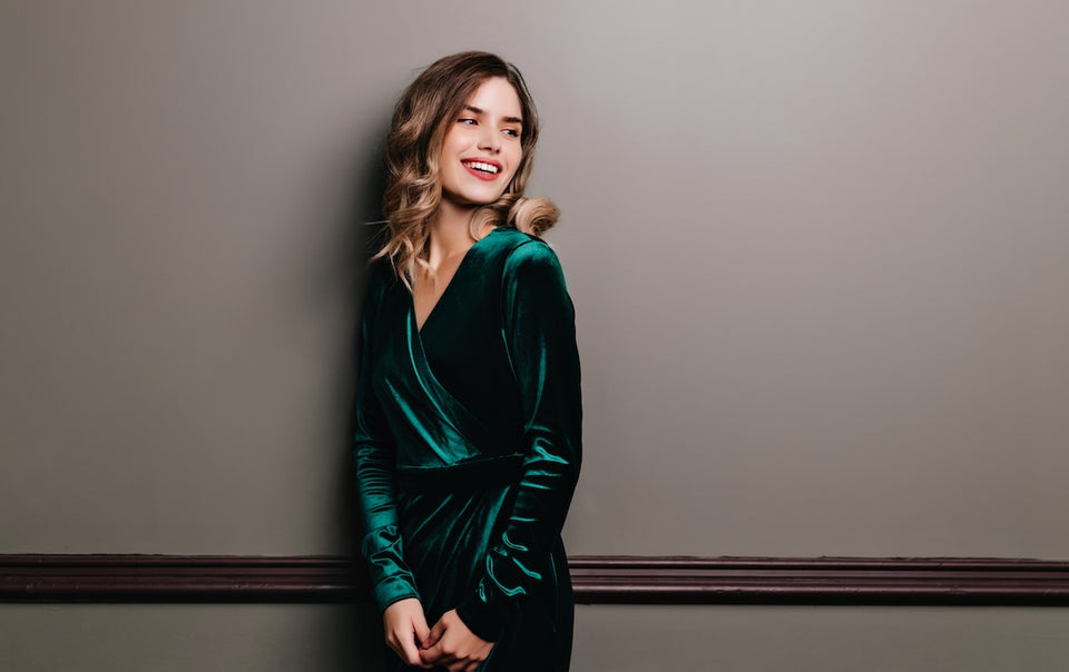 a woman wearing a beautiful wrap around long sleeved green velvet dress