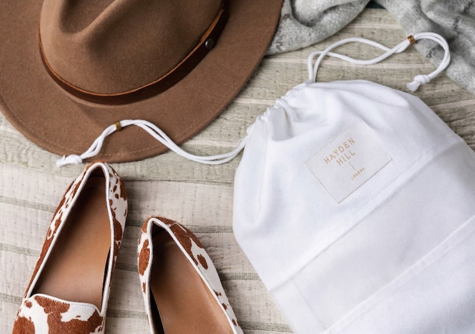 a close up of a Hayden Hill Dust bag next to some ponyskin pumps and a felt hat