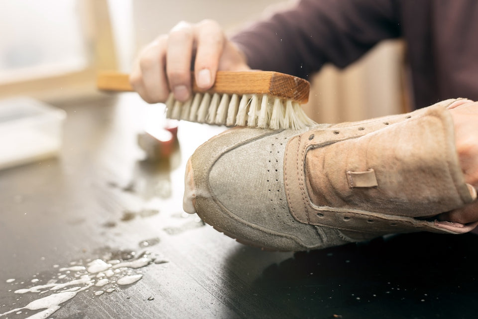 a pair of trainers being cleaned with a brush