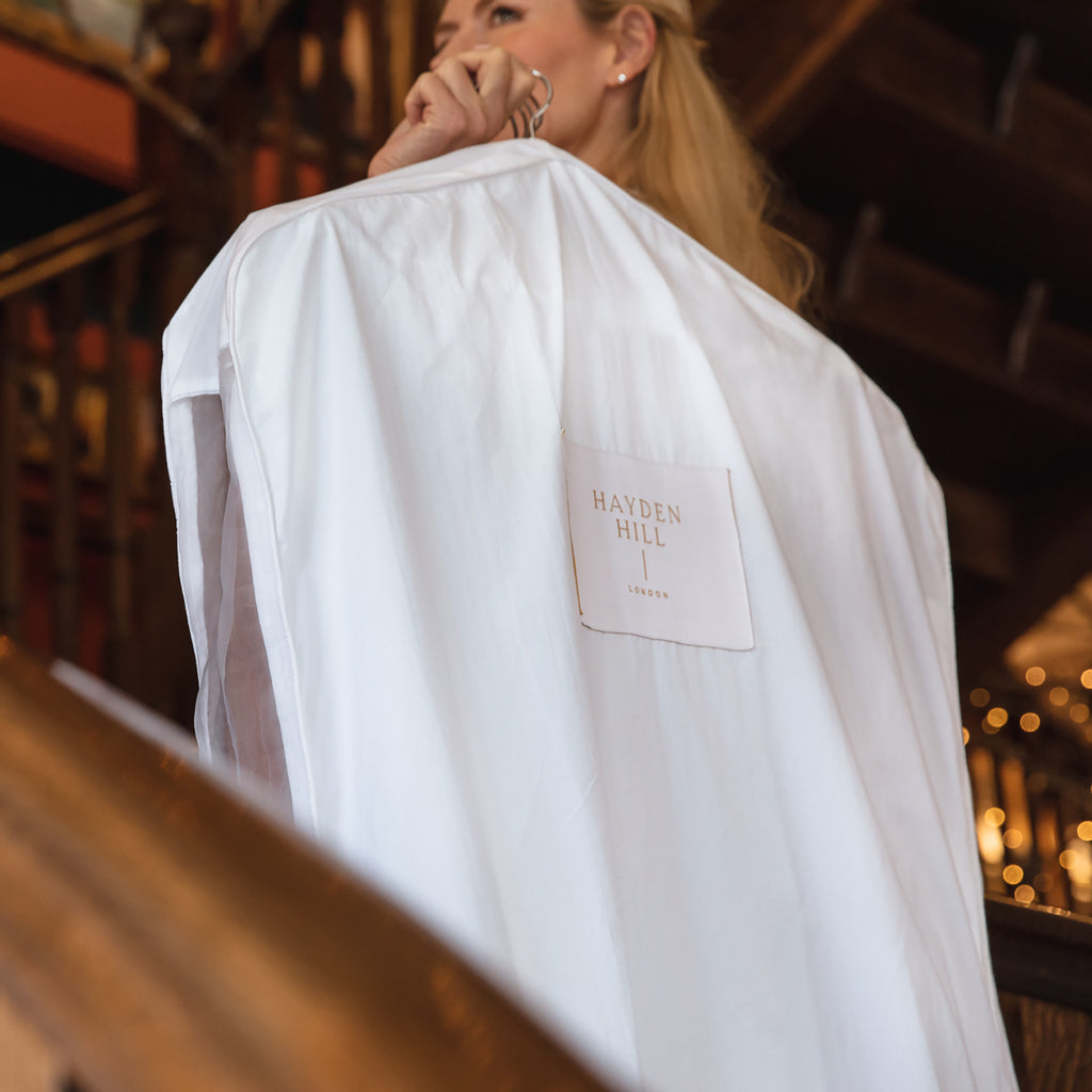 a woman carrying a hanging garment bag over her shoulder