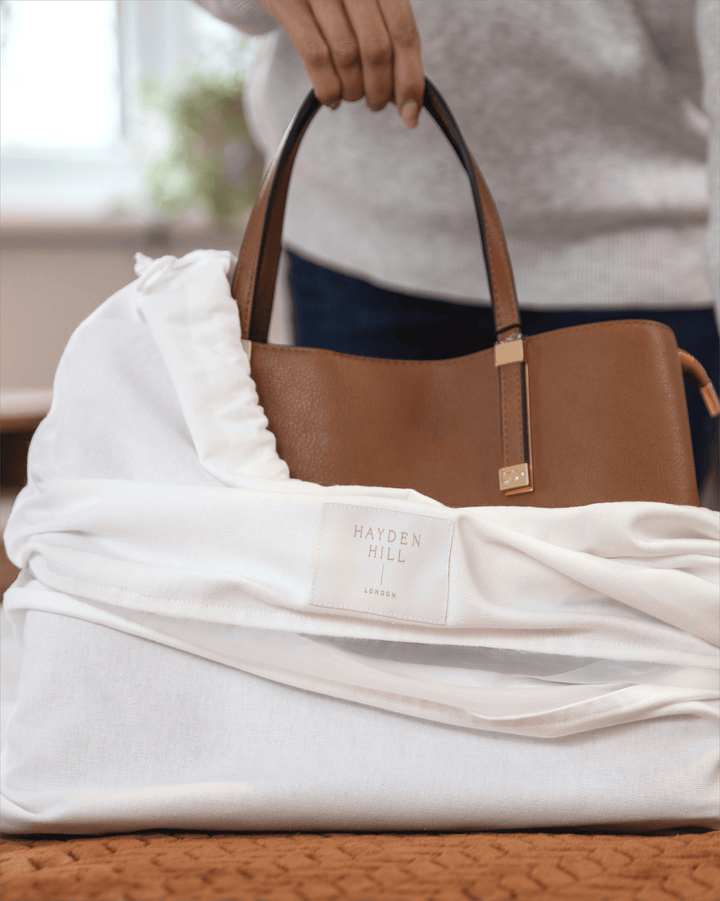 a handbag being placed into a dust bag