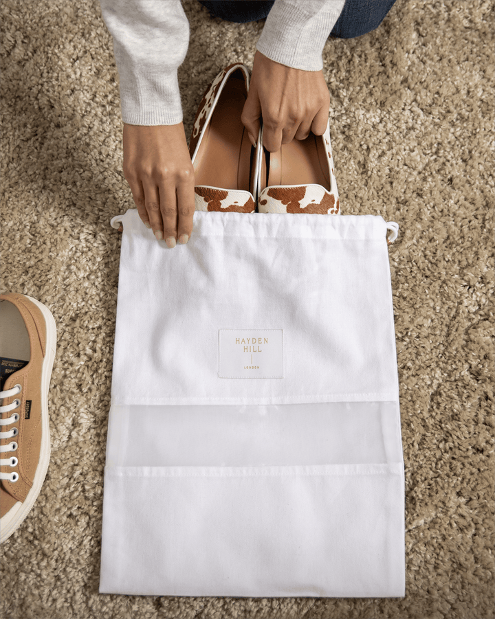 a dust bag lying on carpet with shoes being placed into it