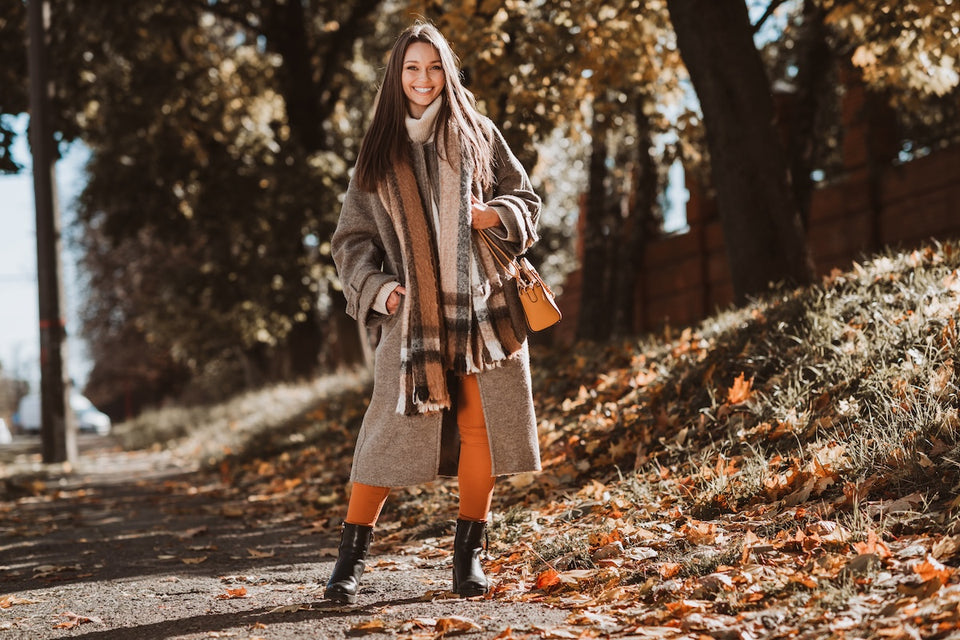 a woman wearing layers of coats and scarves ready on a sunny fall day