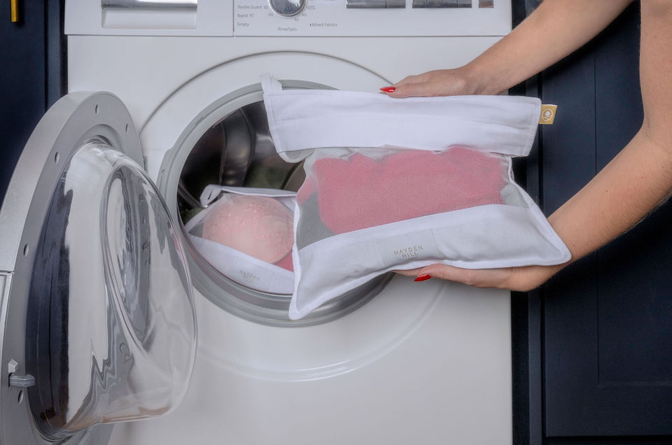 a close up of a Hayden Hill mesh wash bag being placed into the washing machine