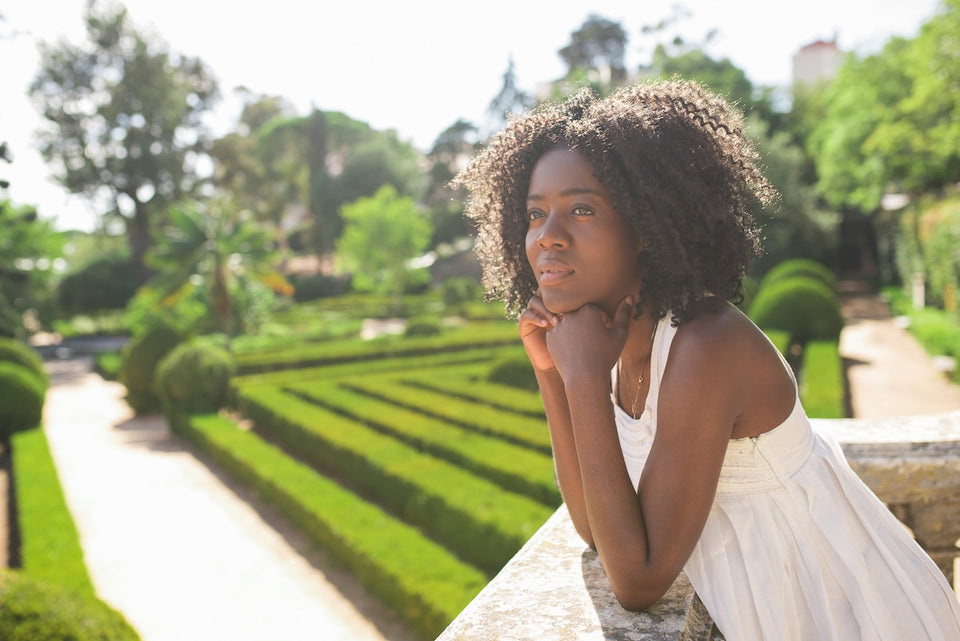 a relaxed woman looking dreamily out on a beautiful garden
