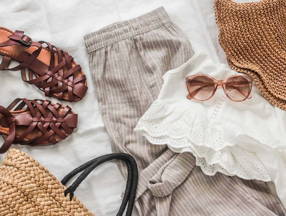 an image of linen trousers, a white top, leather sandals and a straw tote