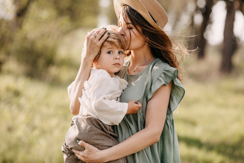 a woman holding a little boy, both wearing vintage clothing