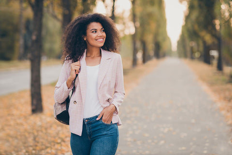 a stylish woman walking through a park wearing denim jeans