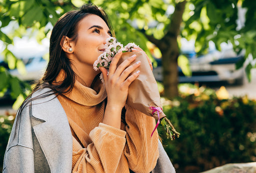 a beautiful woman smelling a bouquet of fresh flowers