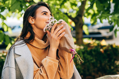 a beautiful woman smelling a bouquet of fresh flowers