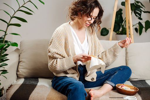 a woman relaxing on the couch at home with a piece of embroidery