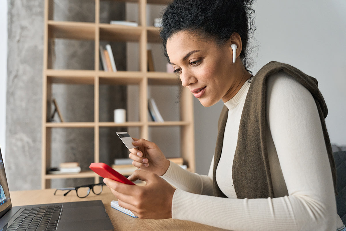 a beautiful woman shopping on her phone holding her credit card