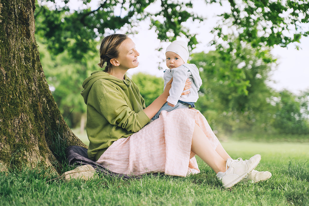 a mother in running shoes, holding her baby on her lap