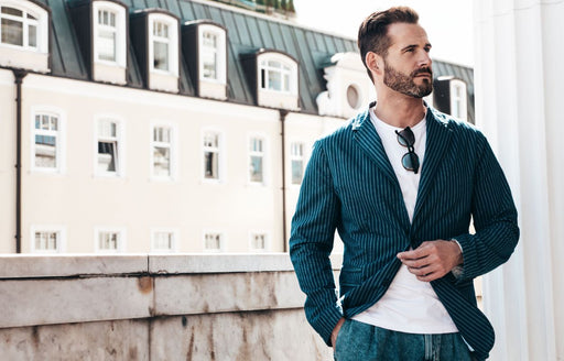 a stylish man wearing a striped blazer, white tee and denim jeans