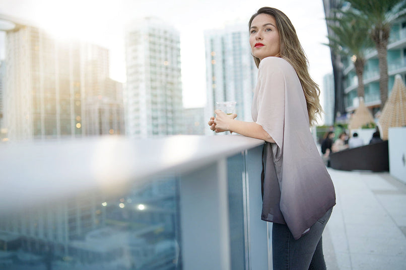 a woman having drinks on a rooftop terrace at dusk