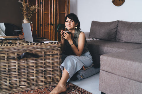a woman using a large wicker basket as a table in her living room