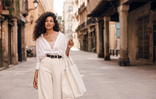 a woman wearing a white shirt and camisole tucked into a pair of cream high waisted pants and belt