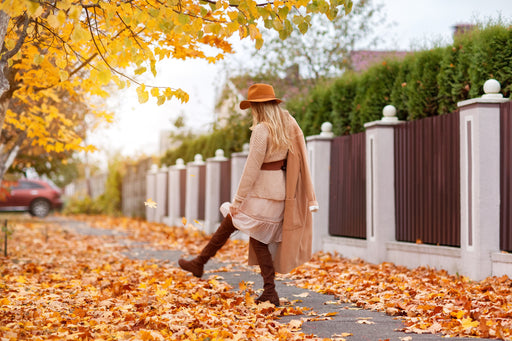 fashionable woman walking through the autumn leaves