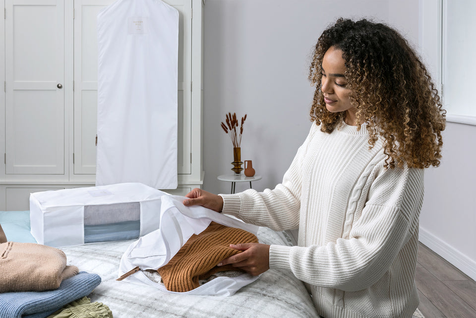 a woman opening a cotton Hayden Hill storage bag to view her tan woolen sweater within