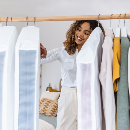 Lady smiling while looking at rail with garment bags