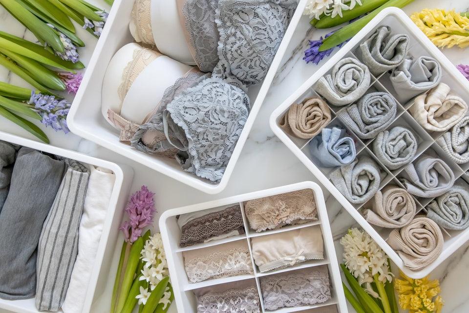 a view from above of several storage boxes with underwear and tees neatly organized, rolled and folded using the Marie Kondo method