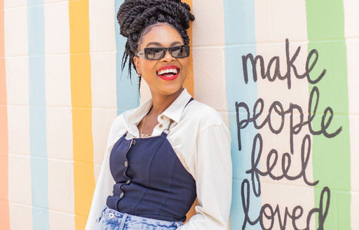 Kat leaning against a brightly painted wall with the wording 