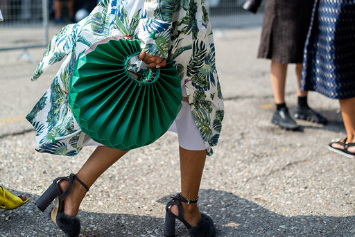 Milan high fashion clothing in close up: a long jungle print shirt and green concertina round purse