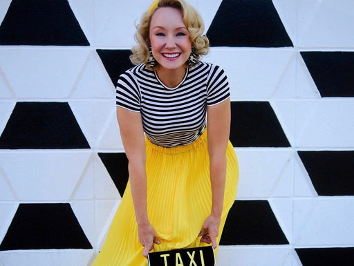 Phoebe wearing a bright yellow pleated skirt and black and white stripe tee