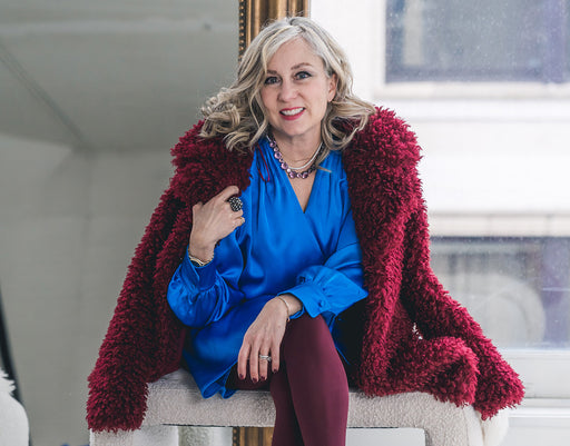 Suze wears a burgundy shaggy wool coat over a blue satin wrap over dress