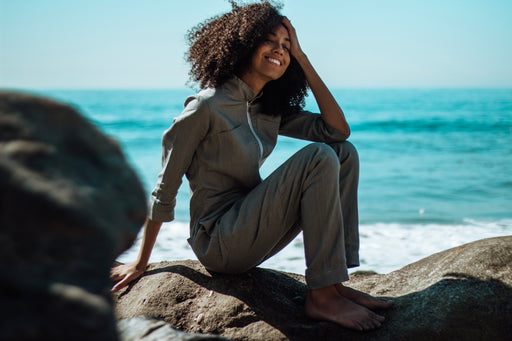 Tyler sitting by the sea wearing a grey jumpsuit