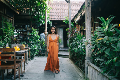 a beautiful woman wearing a stunning silk rust coloured strappy maxi dress