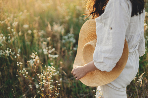 a big brimmed straw hat being carried through a field of wild flowers
