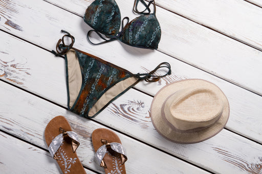 a bikini paired with silver flat sandals and a straw sunhat