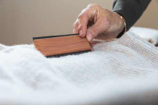 a cashmere comb being used on a soft white woollen pullover