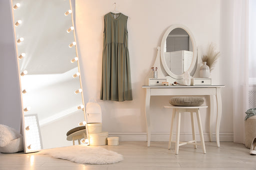a chic dressing area with a well-lit full length mirror, dressing table and stool