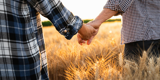 a close of a couple, one wearing a check shirt, one wearing a gingham shirt, holding hands