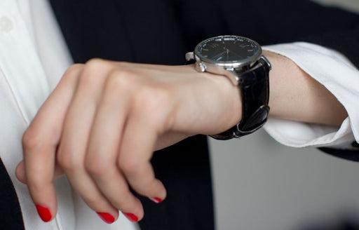 a close up of a hand with bright red nails and a man's wrist watch
