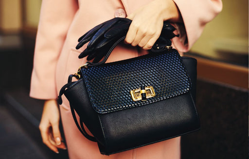 a close up of a woman in a peach coloured coat with black leather bag and gloves