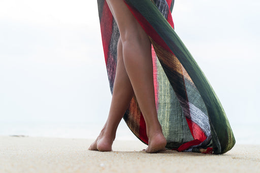 a close up of a woman’s legs wearing a multicolored sarong