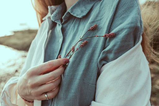 a close up of a woman wearing a gray linen shirt with a pashmina wrap