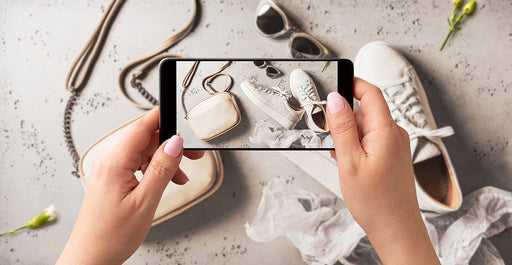 a close up of hands holding a cell phone taking a picture of clothing accessories