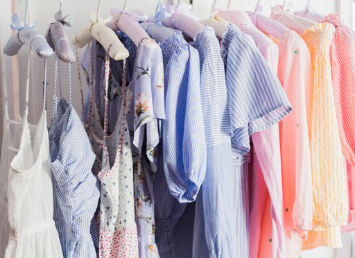 a collection of brightly colored summer clothing on padded satin hangers